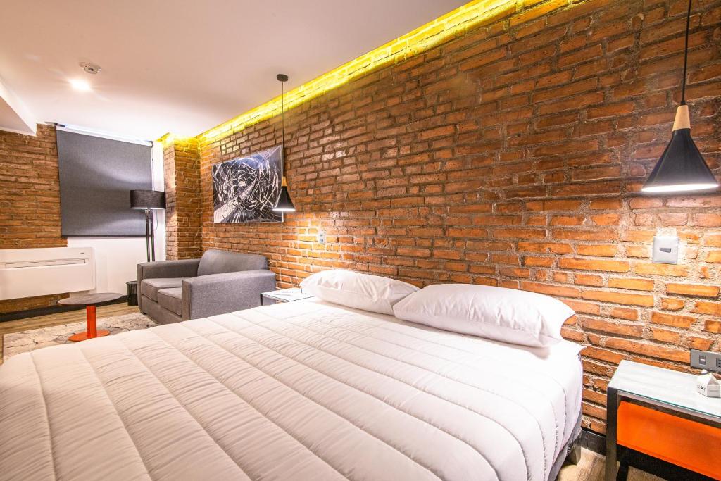 Hostal Boutique Black Cat في سانتياغو: غرفة نوم بحائط من الطوب وسرير