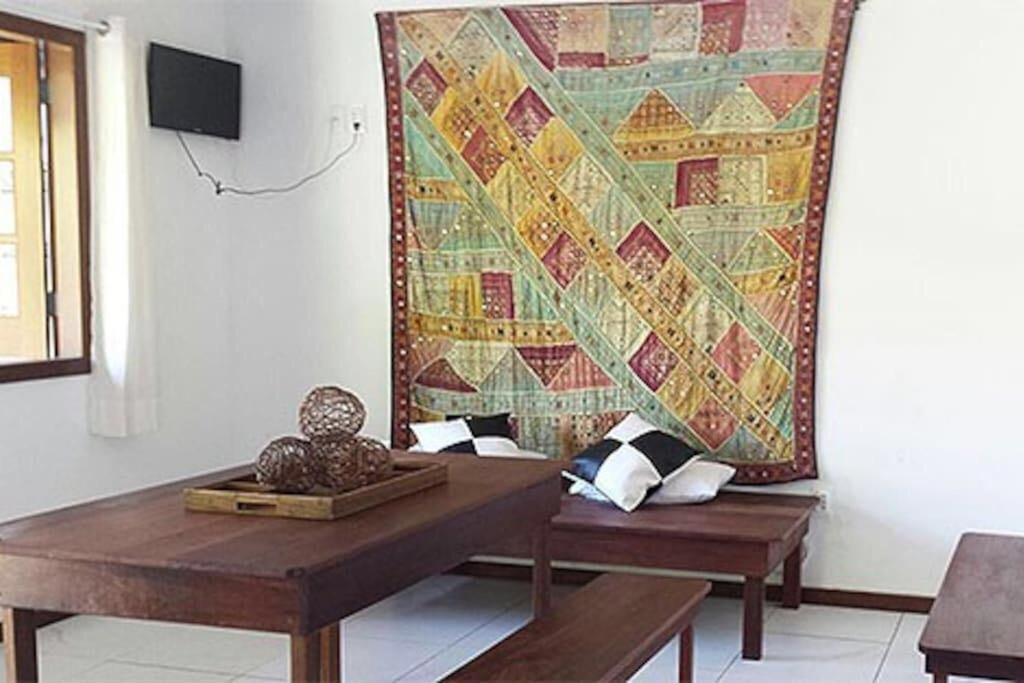 a tapestry hanging on a wall in a living room with a table at Casas Coloniais in Morro de São Paulo