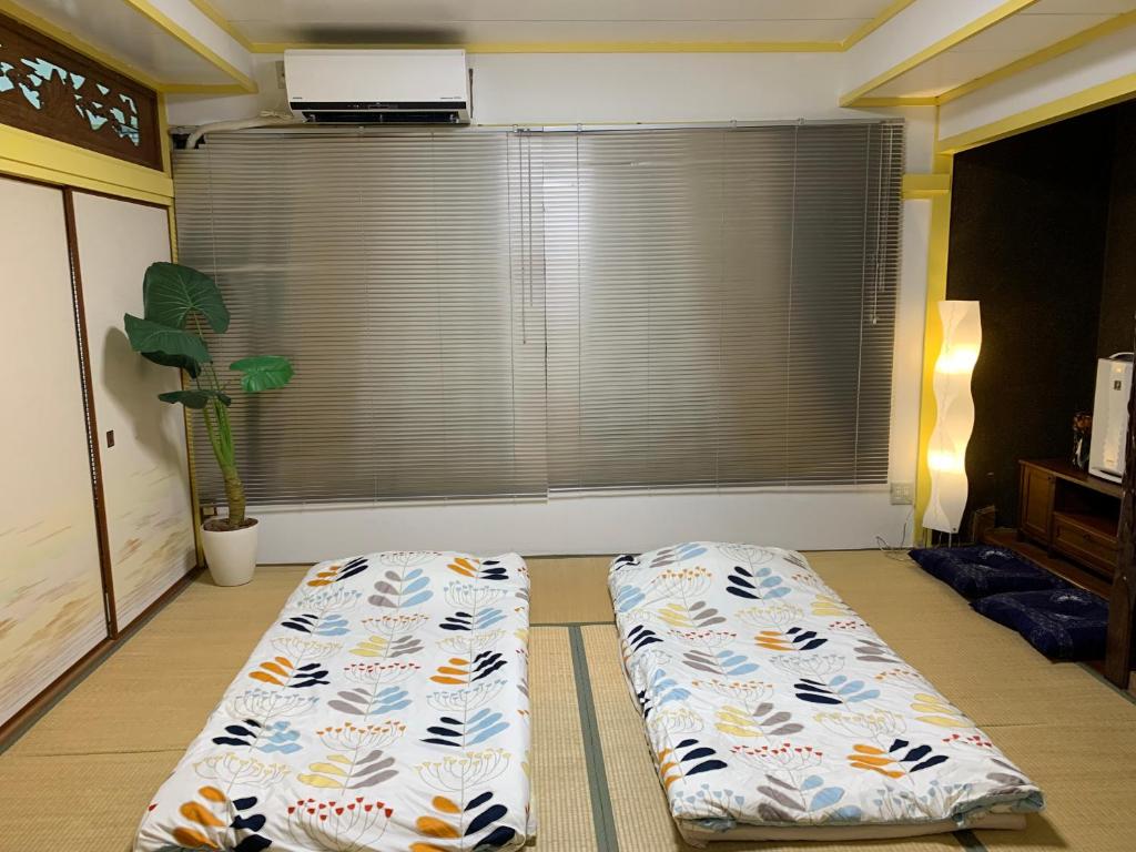 2 Betten im Wohnzimmer mit Fenster in der Unterkunft 海天house in Beppu