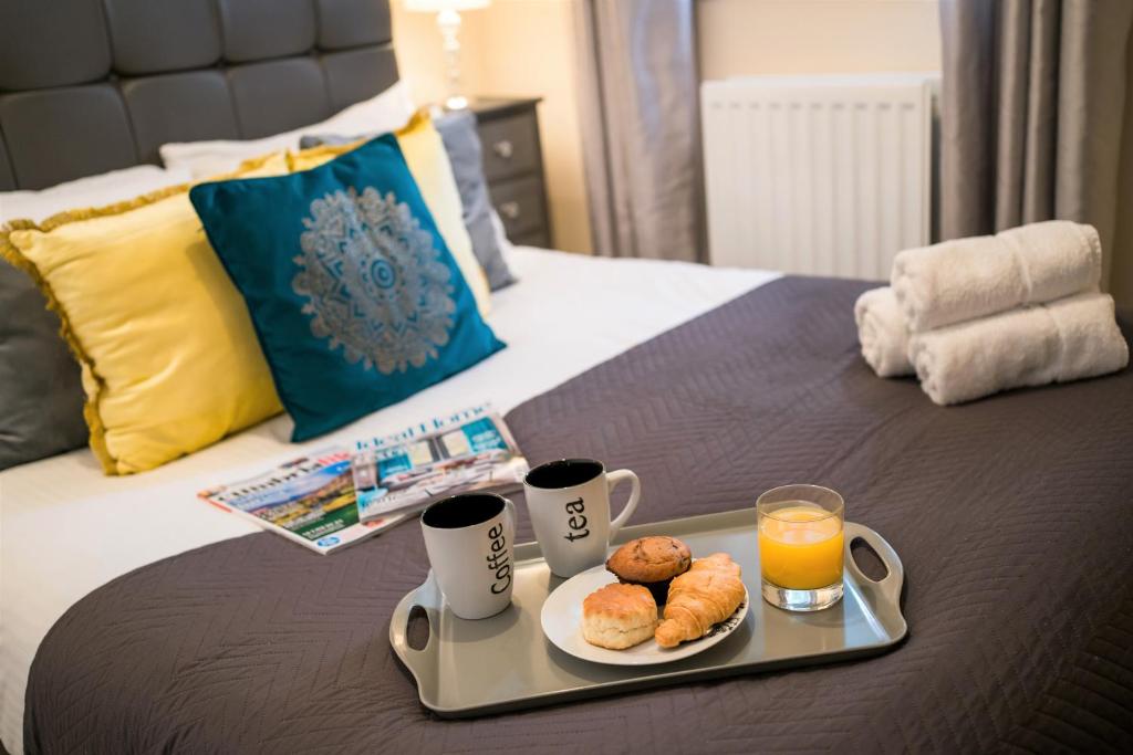 ein Tablett mit zwei Tassen Orangensaft und Donuts auf dem Bett in der Unterkunft Wordsworth Apartment Irene court in Cockermouth