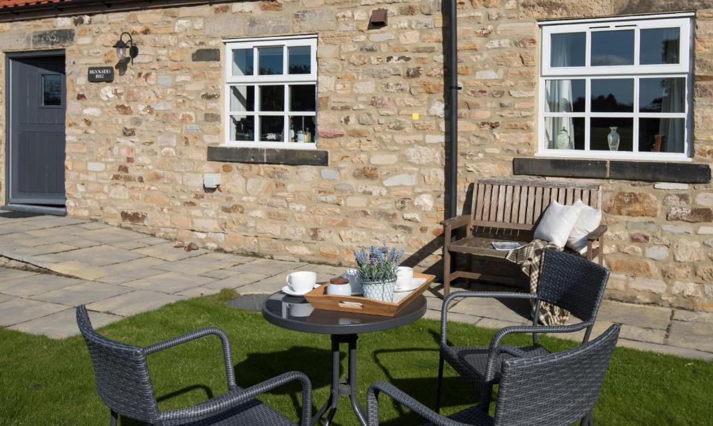 eine Terrasse mit Stühlen, einem Tisch und einer Bank in der Unterkunft Brooksides Byre Durham Country Cottage in Durham