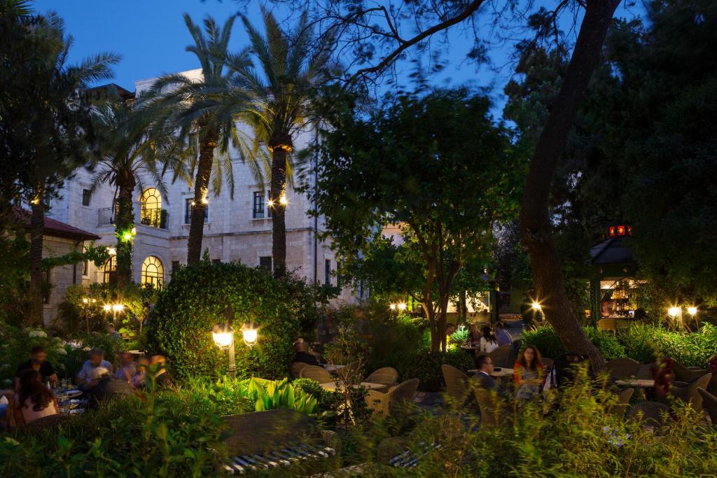 a group of people sitting in a garden at night at The American Colony Hotel - Small Luxury Hotels of the World in Jerusalem