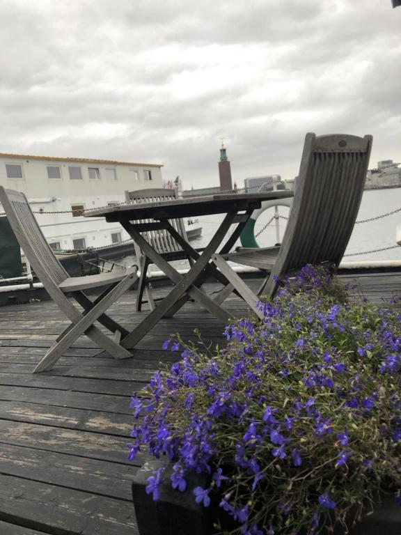 a picnic table and two chairs and flowers on a dock at Den Röda Båten in Stockholm
