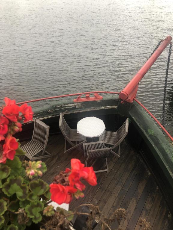 a boat with a table and chairs on the water at Den Röda Båten in Stockholm