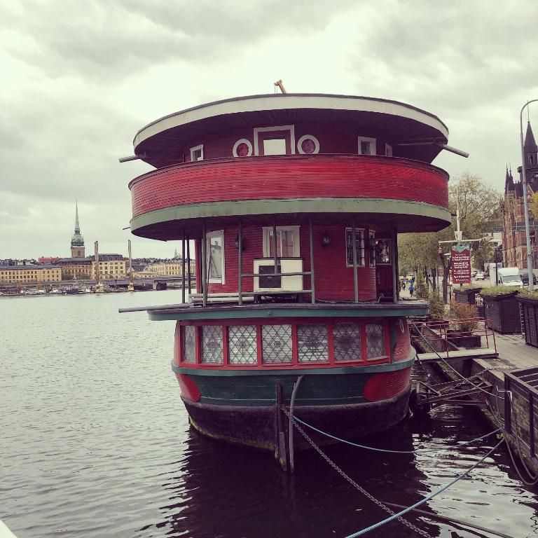 a red boat is docked in the water at Den Röda Båten in Stockholm