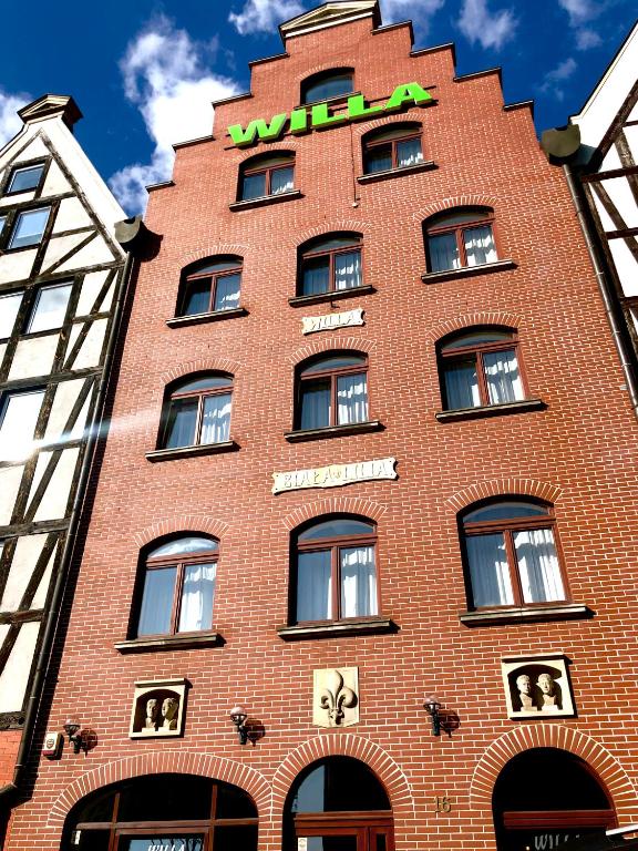ein rotes Backsteingebäude mit einem Schild darauf in der Unterkunft Willa Biala Lilia Old Town in Danzig