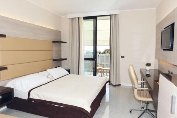 sypialnia z łóżkiem, biurkiem i telewizorem w obiekcie Hotel San Carlo w Lignano Sabbiadoro