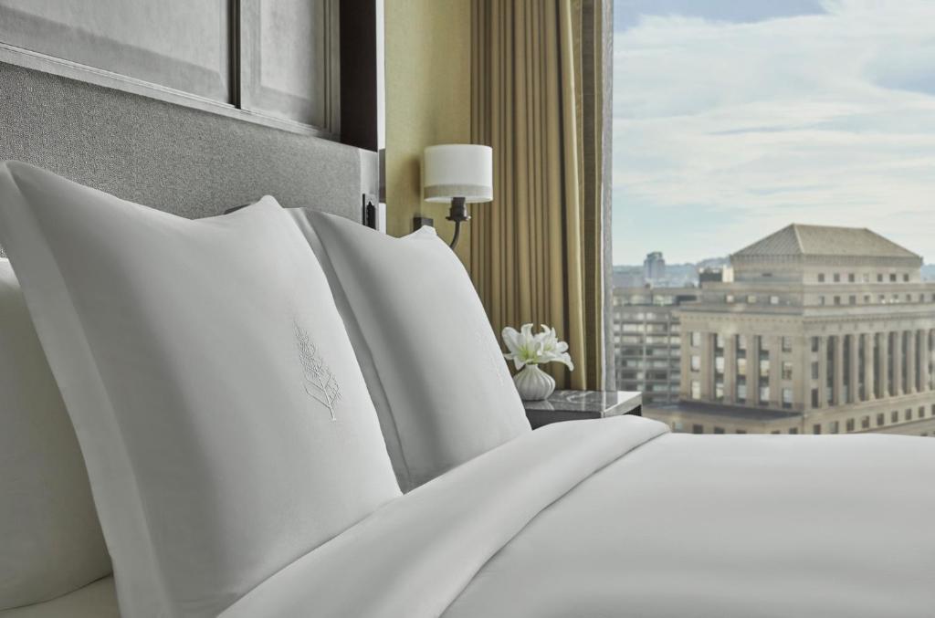 a bed with white pillows in a room with a window at Four Seasons Hotel One Dalton Street, Boston in Boston