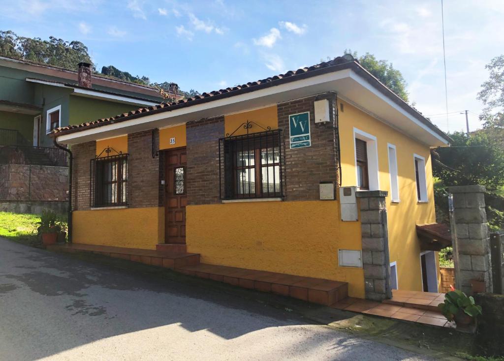 un pequeño edificio amarillo con una puerta en una calle en Casa Valle, en Cangas de Onís