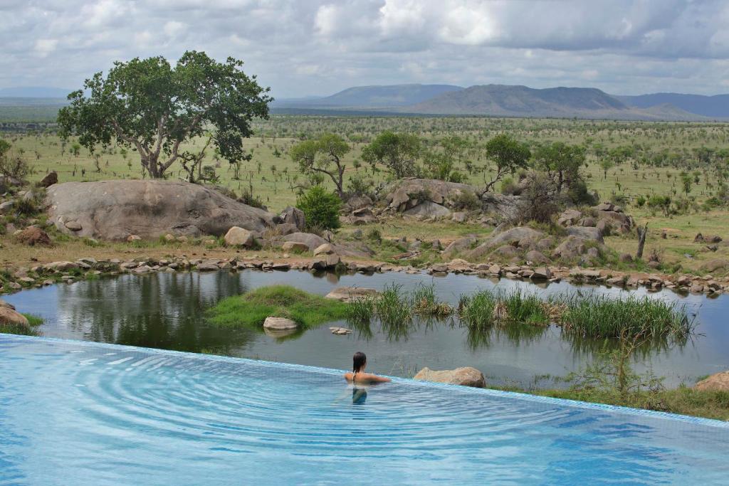 
a person in the water with a surfboard at Four Seasons Safari Lodge Serengeti in Banagi
