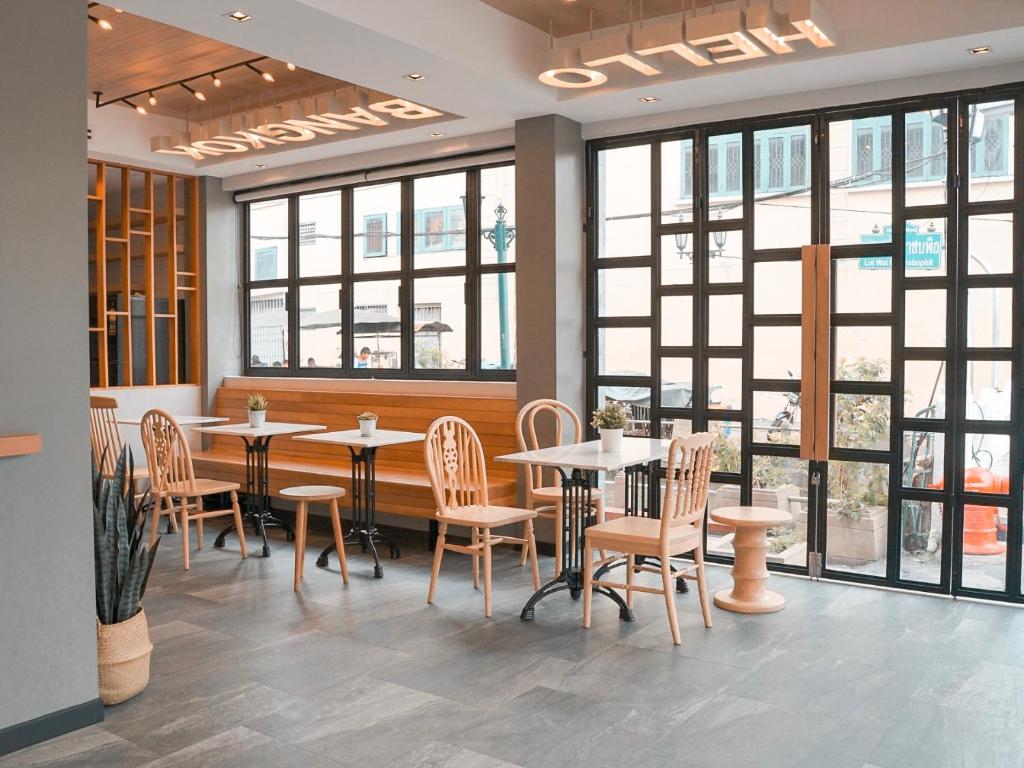 a restaurant with tables and chairs and windows at YAKTHAI POSHTEL in Bangkok