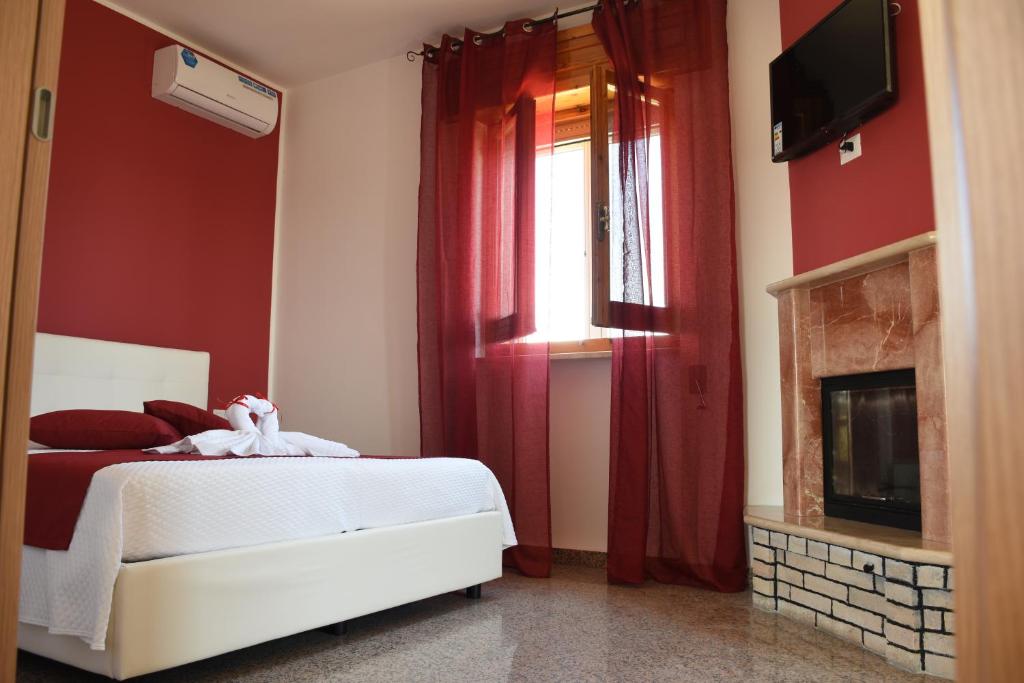 1 dormitorio con 1 cama con paredes rojas y chimenea en La Pescarella en Ginosa