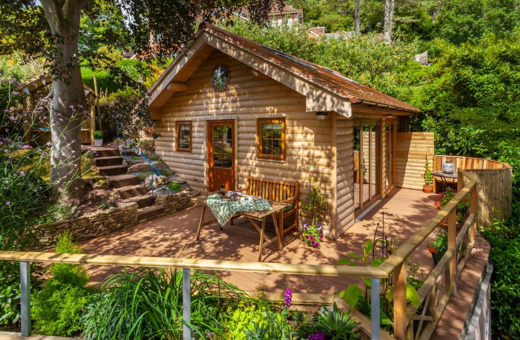a log cabin in the woods with a table and chairs at Porthole Log Cabin in Minehead