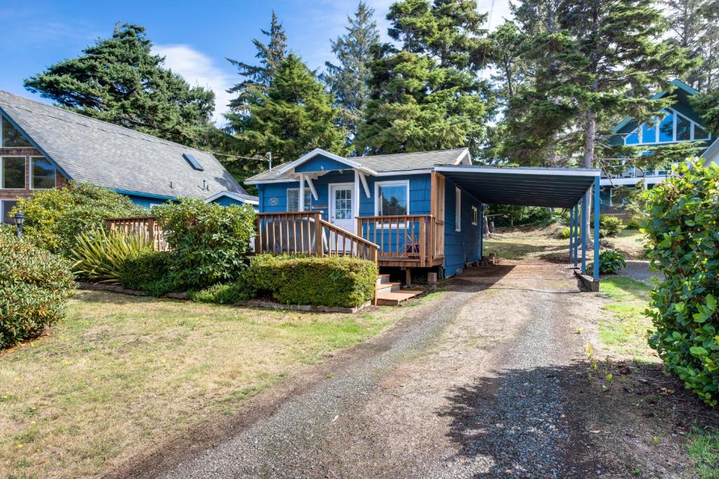 a blue house with a garage next to a driveway at Kiwi's Cottage in Gleneden Beach