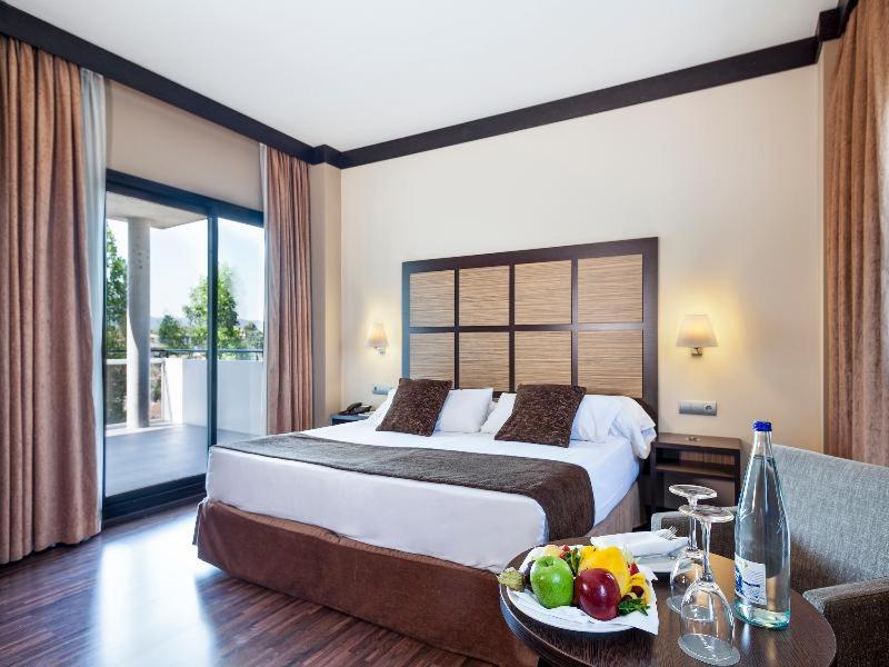 サバデイにあるAparthotel Attica 21 Vallésのホテルルーム(ベッド1台、テーブル、フルーツボウル付)