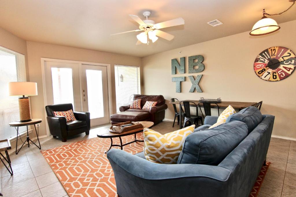 a living room with a couch and chairs and a clock at Riverside Retreat in New Braunfels