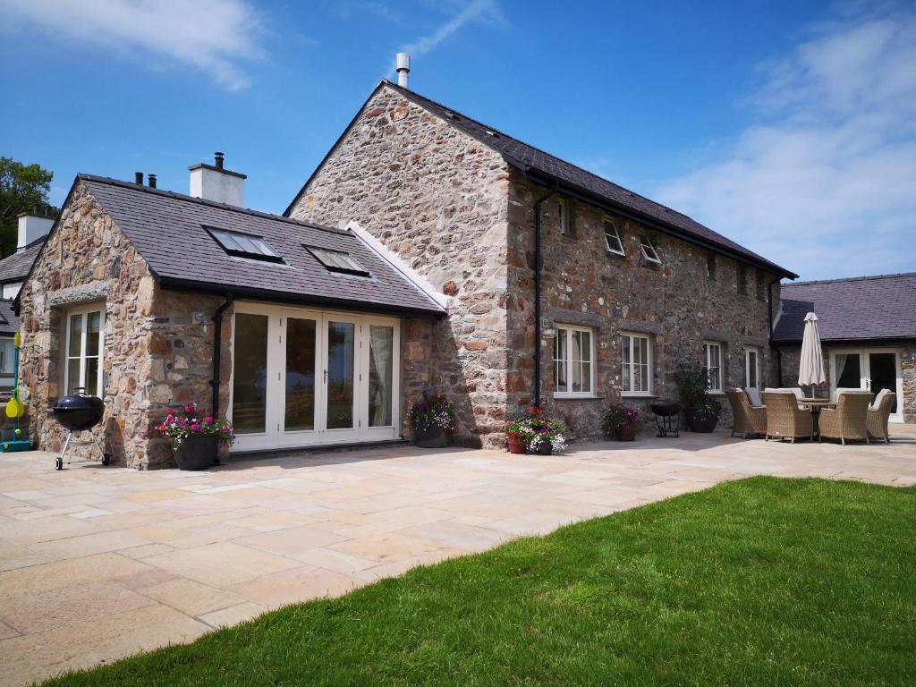 a stone house with a patio in front of it at Penrhyn Barn in Penrhos-Lligwy