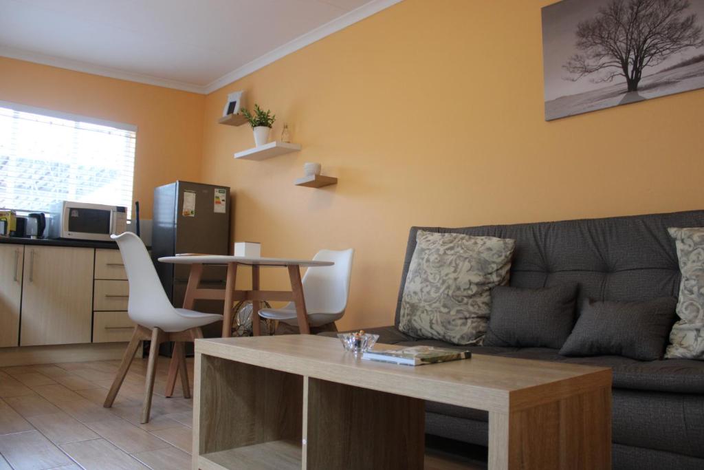 uma sala de estar com um sofá e uma mesa em Lovely Linden Cottage with Solar Inverter em Joanesburgo