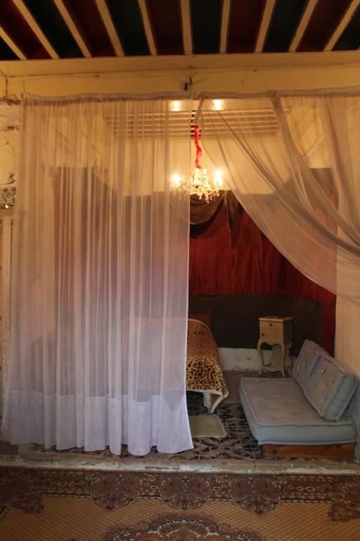Habitación con cortina, sofá y cama en Maison du 18ème Siècle en Túnez