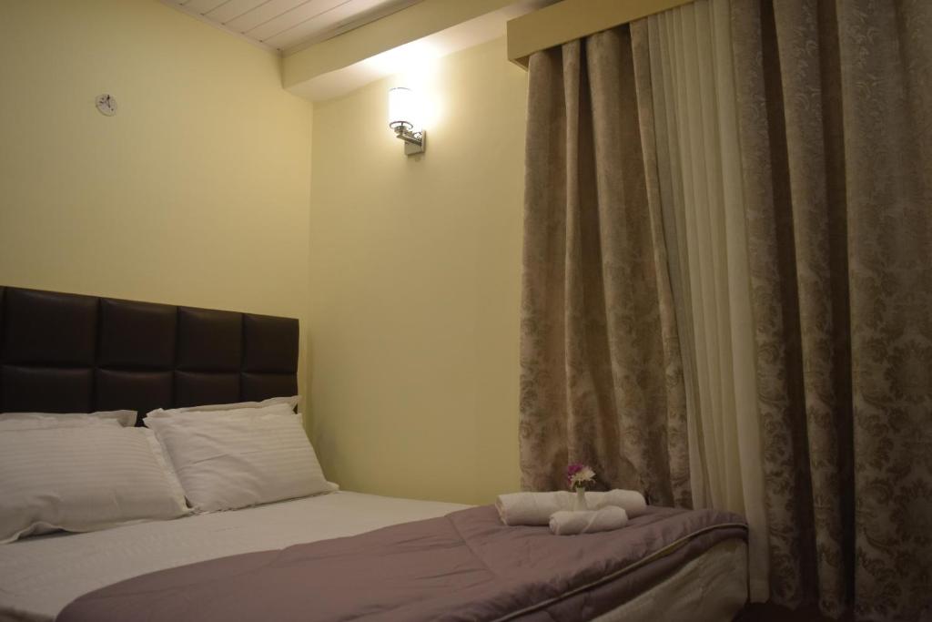 a bedroom with a bed and a window with a curtain at Denzong Khim in Gangtok