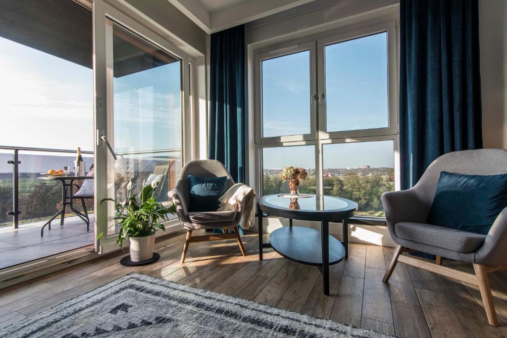 salon ze stołem i krzesłami oraz dużymi oknami w obiekcie Panorama Suite - Top Apartment - Gliwice w mieście Gliwice