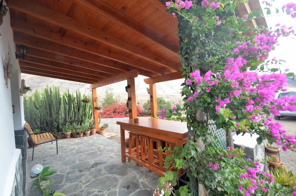 un banco de madera en un patio con flores rosas en Casa Caballería en Vallebrón