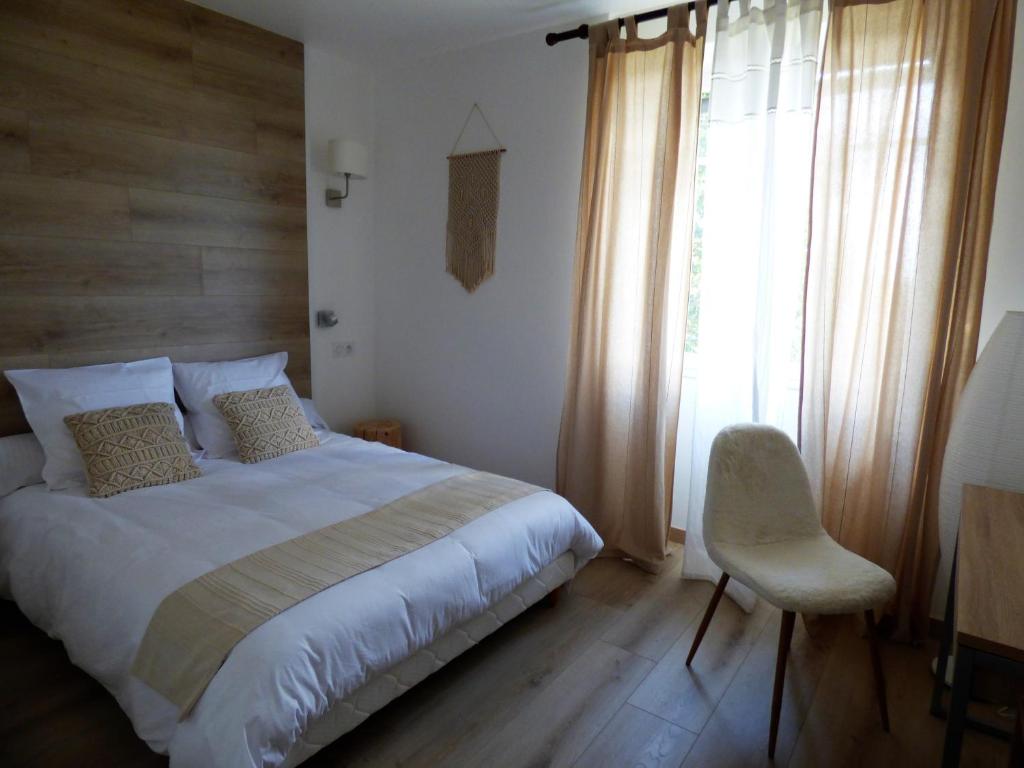 a bedroom with a bed and a chair and a window at Les Hauts de Malirat in Capdenac-Gare