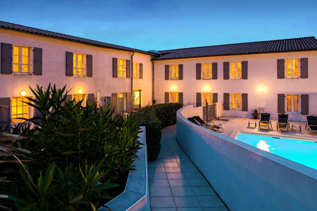 a building with a swimming pool next to a building at Appart'hotel Perle de Ré in La Couarde-sur-Mer