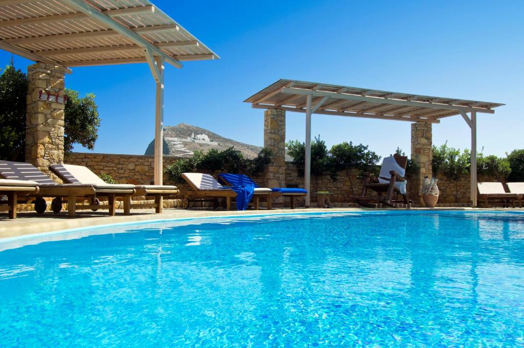 a swimming pool with a pergola and chairs and a swimming pool at Kallisti Hotel in Chora Folegandros