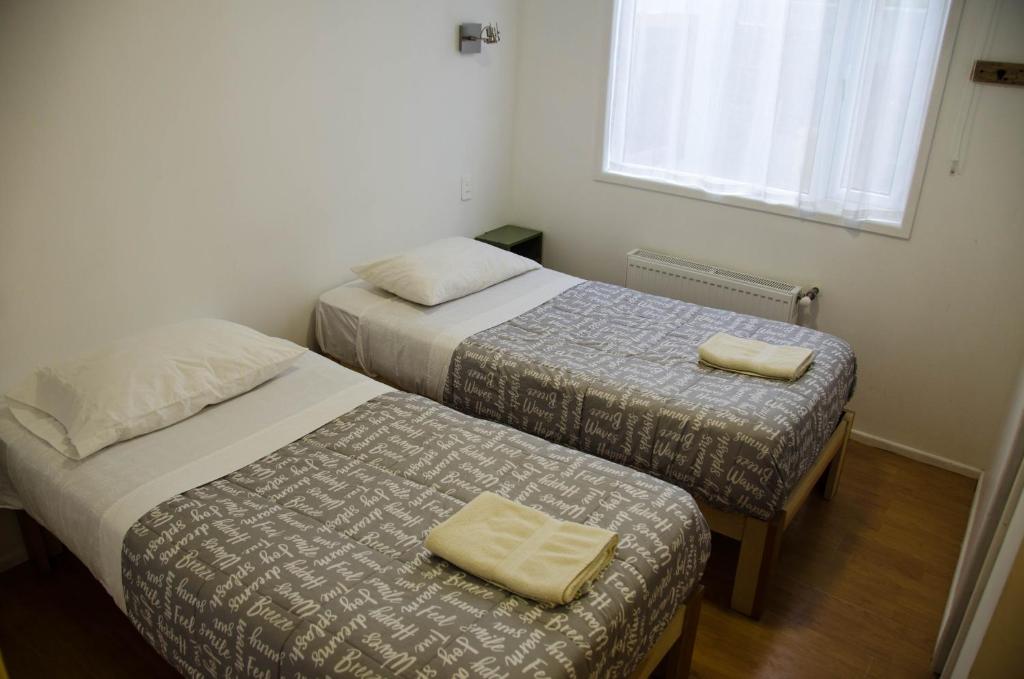 two beds in a small room with a window at El Patagónico Hostel in Puerto Natales