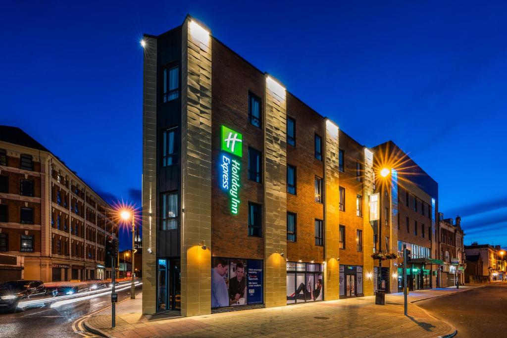 a building on a city street at night at Holiday Inn Express - Derry - Londonderry, an IHG Hotel in Derry Londonderry