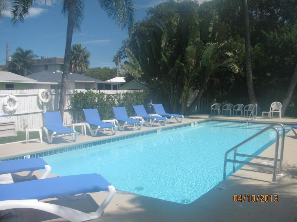 a swimming pool with blue chairs and a bunch oficans at Queens Gate Resort in Bradenton Beach