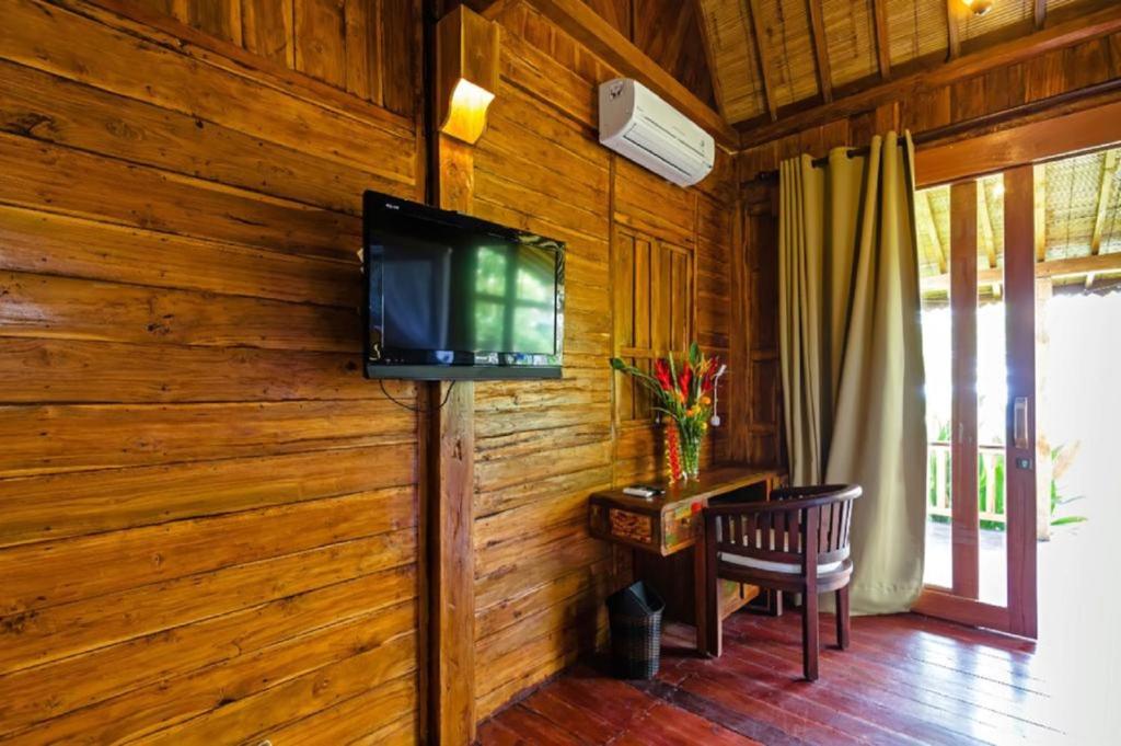 a living room with a television on a wooden wall at Bali Natha Beach Front in Canggu