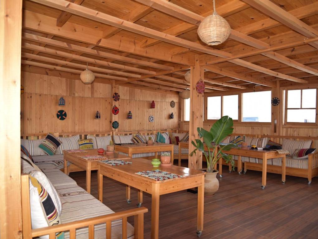 a dining room with wooden tables and couches at Dar Surf in Taghazout