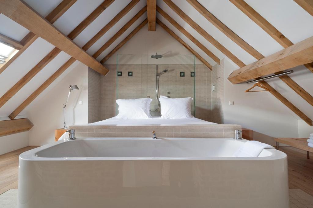 a large white bath tub in a room with a bed at Cour 8 Lofts in Maastricht