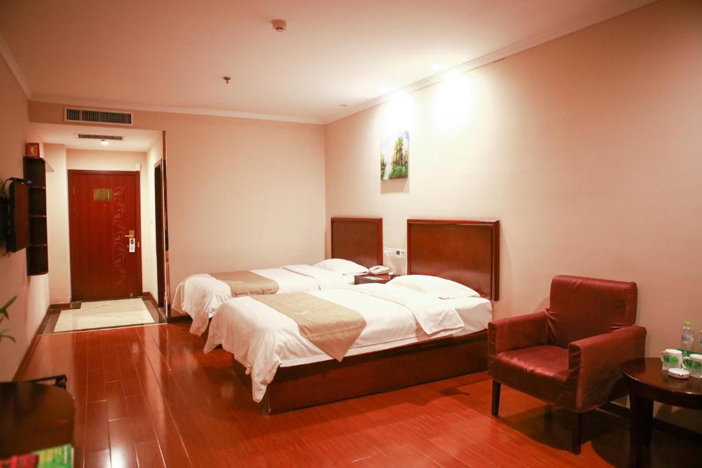 een slaapkamer met 2 bedden en een stoel bij GreenTree Inn Puyang Fan County People Avenue Banqiao Road Hotel in Yancunpu