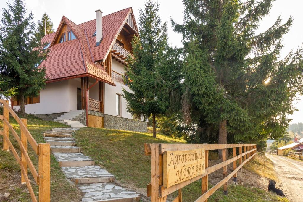 a house with a sign in front of it at Agropensiunea Mara in Mărişel