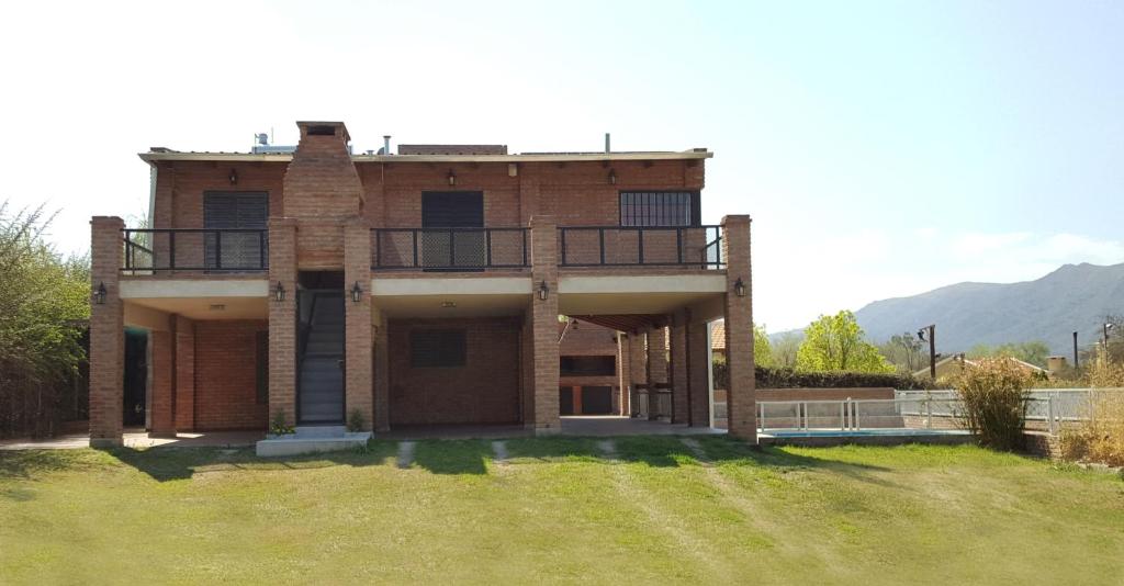 a large brick house with a balcony on a yard at Mardi - Departamentos de alquiler temporario in Bialet Massé