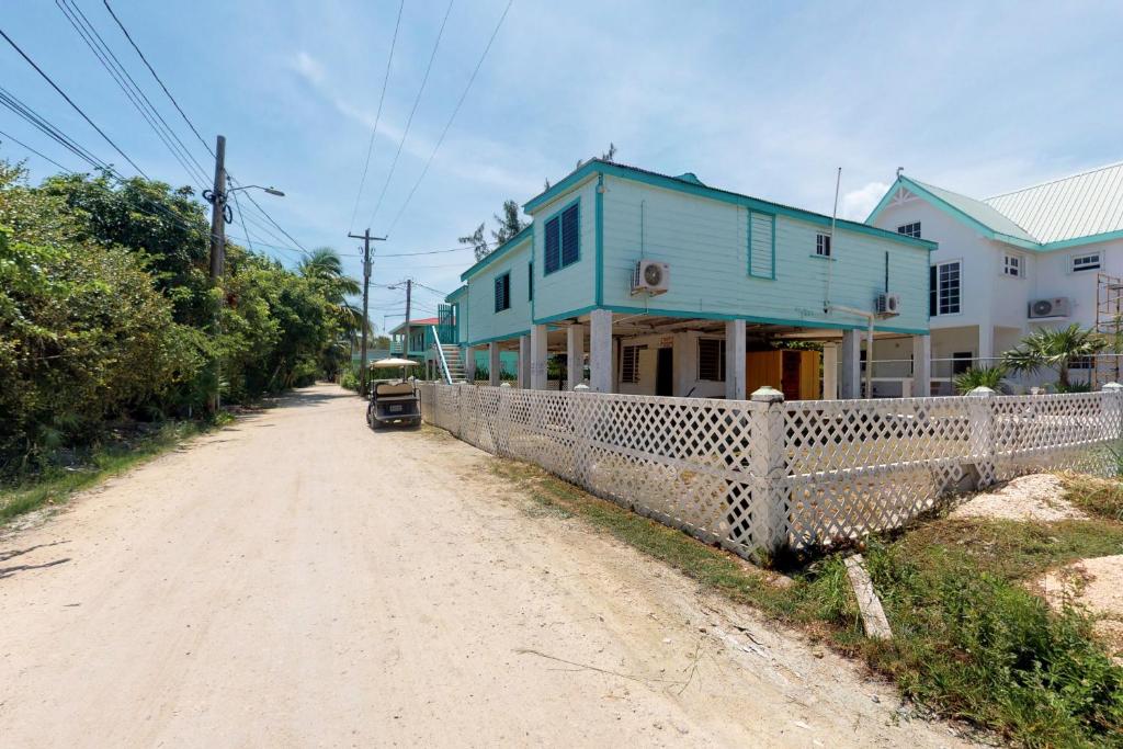 a blue house on the side of a dirt road at Princesa Angienelle in Caye Caulker