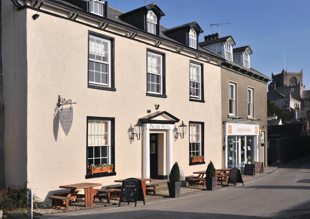 a building with tables and benches in front of it at Priory hotel in Cartmel