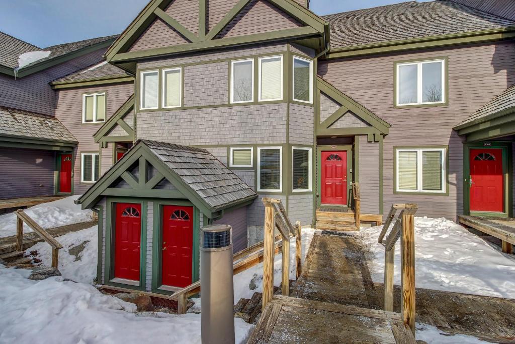 una casa con puertas rojas en la nieve en The Jay Chalet, en Jay