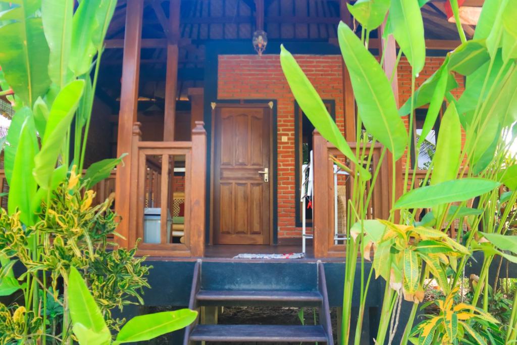 una casa con una puerta de madera y algunas plantas en Pondok Balian, en Selemadeg