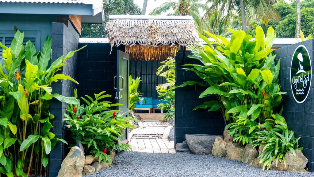 a resort entrance with a black building with plants at Casa Del Sol in Rarotonga