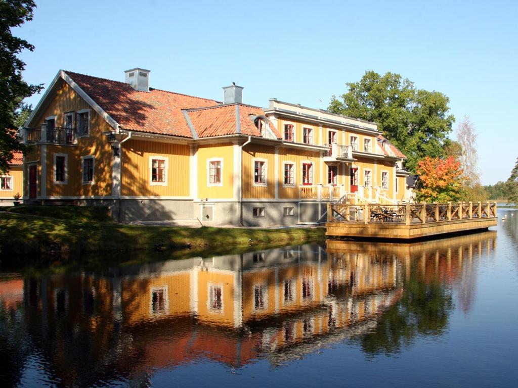 une maison sur une rivière avec sa réflexion dans l'eau dans l'établissement Dufweholms Herrgård, à Katrineholm