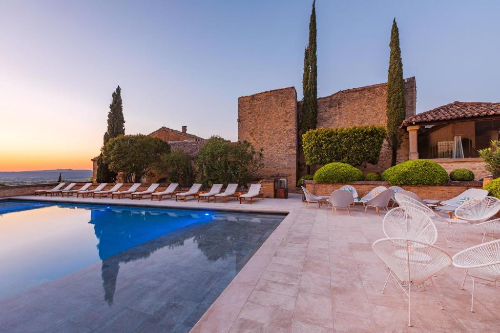 une piscine avec des chaises longues et une maison dans l'établissement Le Vieux Castillon, à Castillon-du-Gard