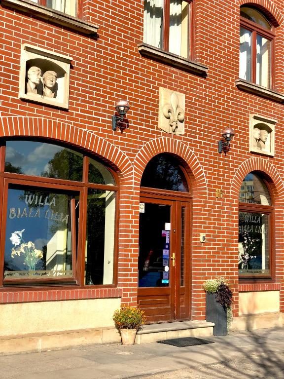 ein rotes Backsteingebäude mit einer großen Tür und Fenstern in der Unterkunft Willa Biala Lilia Old Town in Danzig