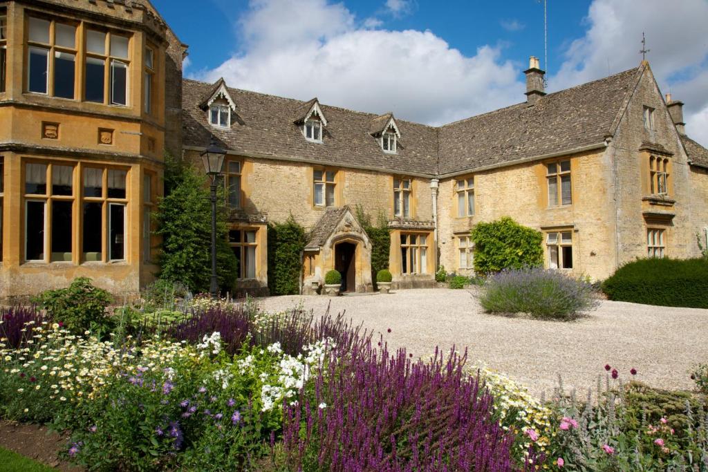 una antigua casa de piedra con un jardín delante de ella en Lords Of The Manor en Upper Slaughter