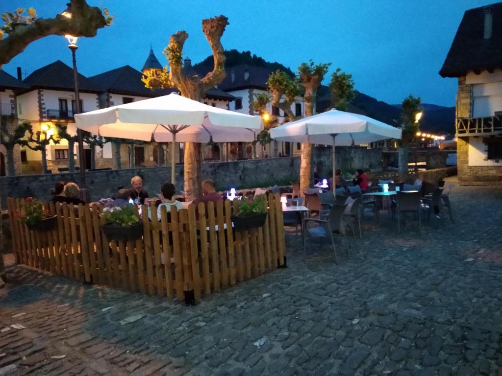 a restaurant with tables and umbrellas at night at Hostal Orialde in Ochagavía