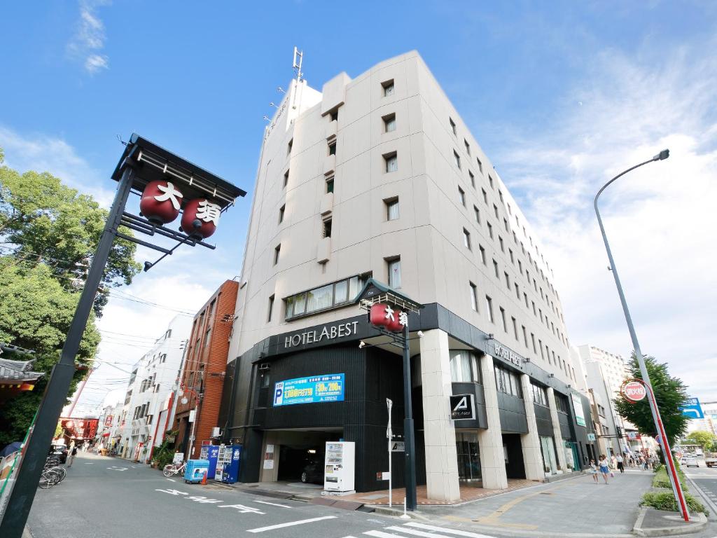 a tall white building on a city street with a traffic light at Hotel Abest Osu Kannon Ekimae Hane no Yu in Nagoya