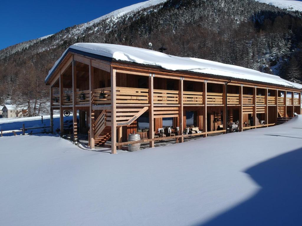 un bâtiment avec un toit enneigé dans la neige dans l'établissement La Tresenda Hotel and Mountain Farm, à Livigno